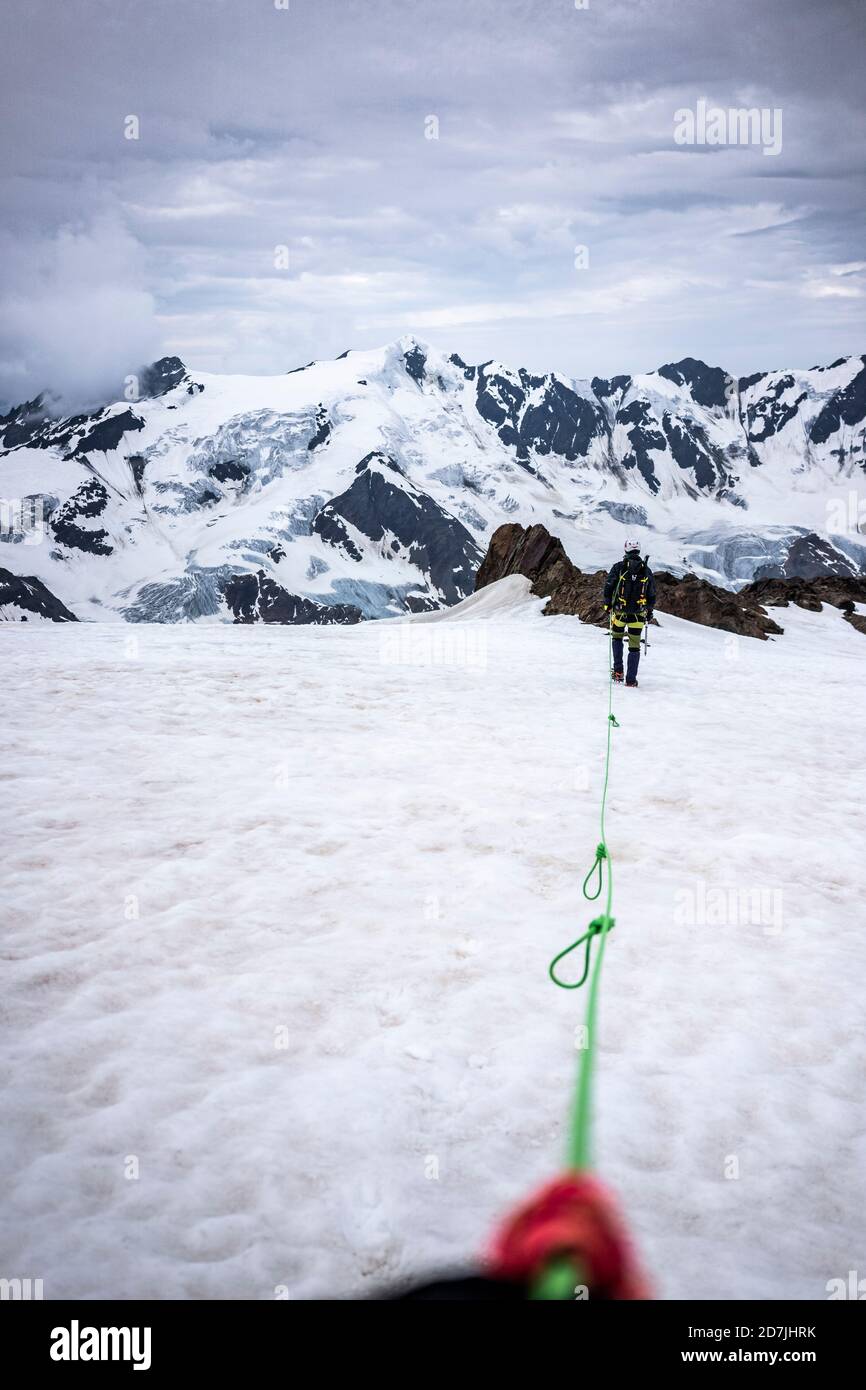 Mature man with rope walking on snow covered landscape against sky, Stelvio National Park, Italy Stock Photo