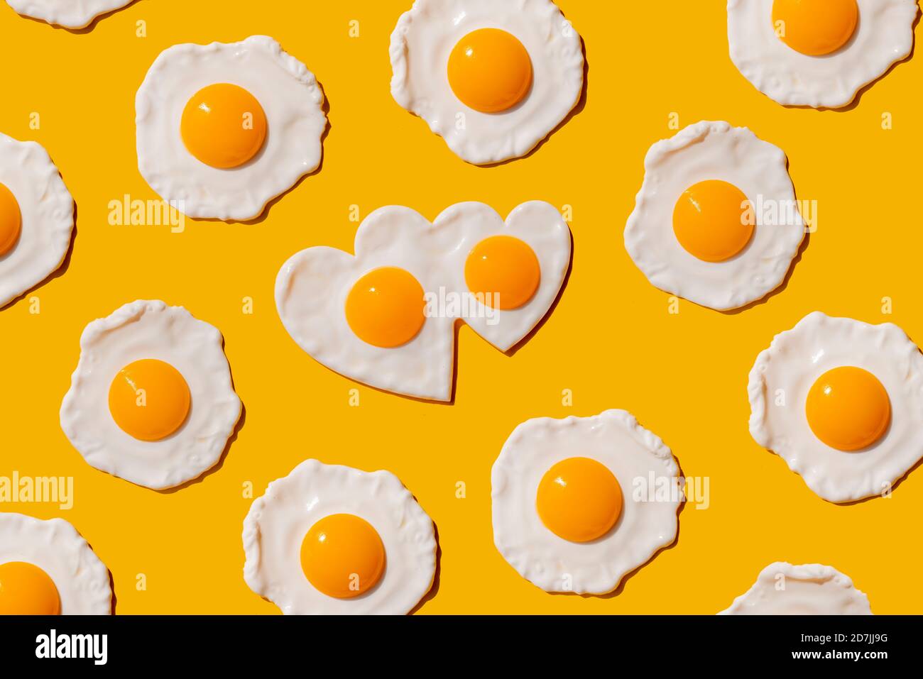 Pattern of fried eggs against yellow background Stock Photo