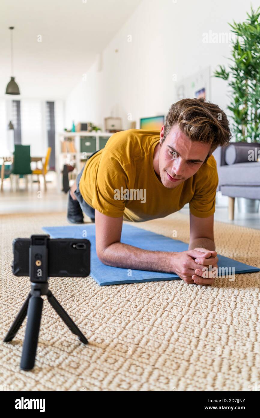 Fitness trainer live streaming plank exercise at home Stock Photo