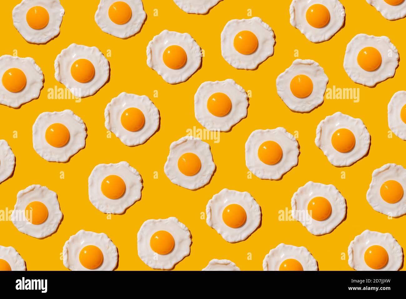 Pattern of fried eggs against yellow background Stock Photo