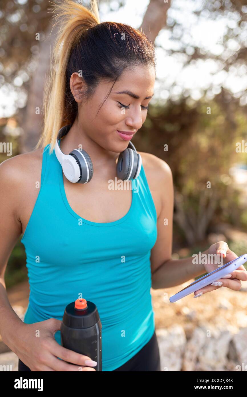 Smiling Hispanic woman using smart phone Stock Photo