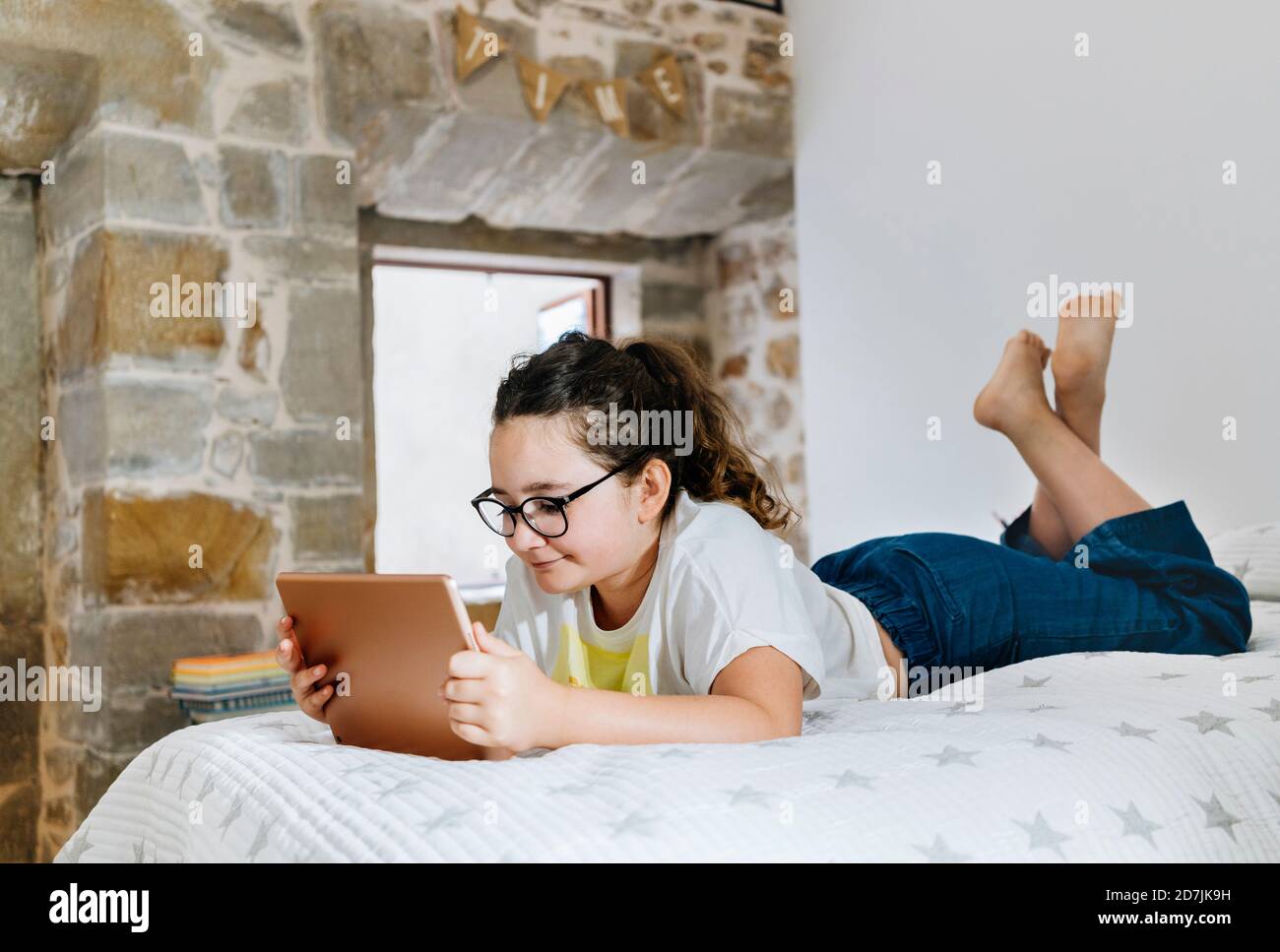 Girl lying on front while using digital tablet at home in bedroom Stock ...