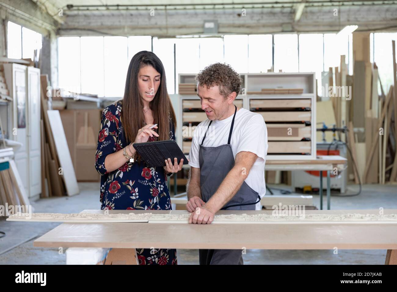 Interior designer showing digital tablet to carpenter while standing at workshop Stock Photo