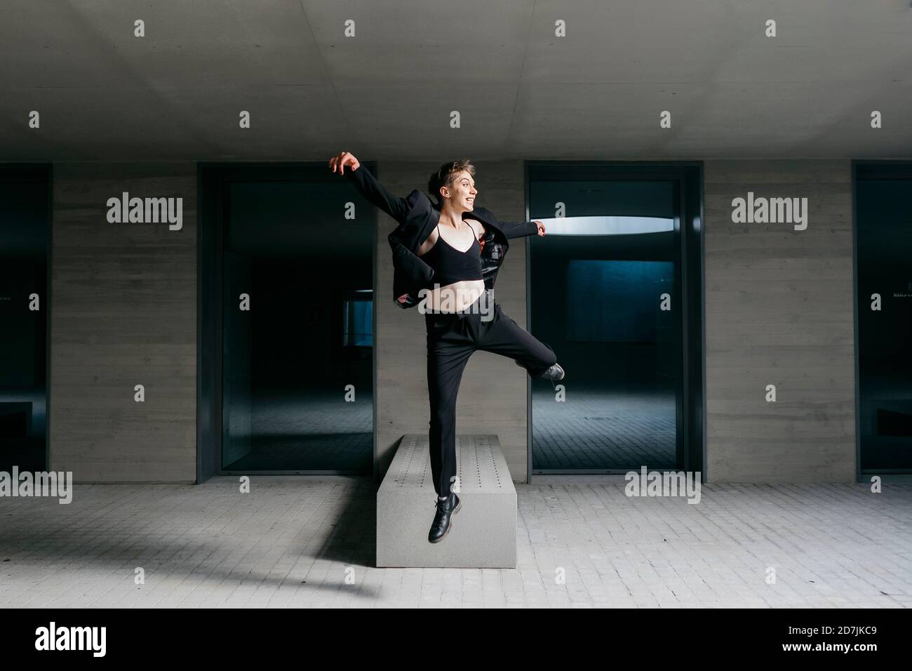 Non-binary young man wearing black suit dancing in basement Stock Photo