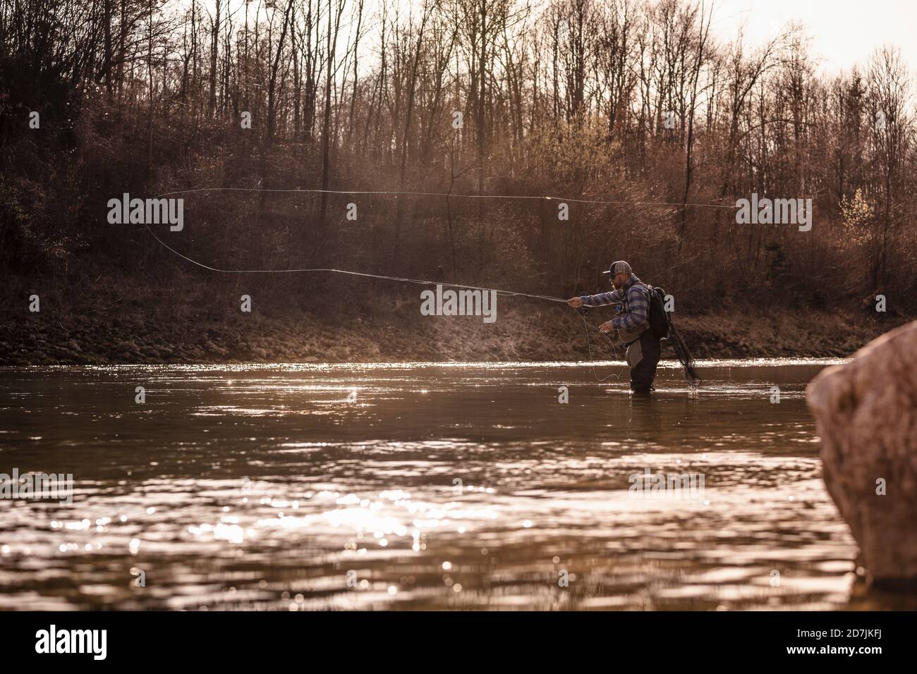 Fly fisherman throwing fishing reel in river to catch fish during sunset  Stock Photo - Alamy