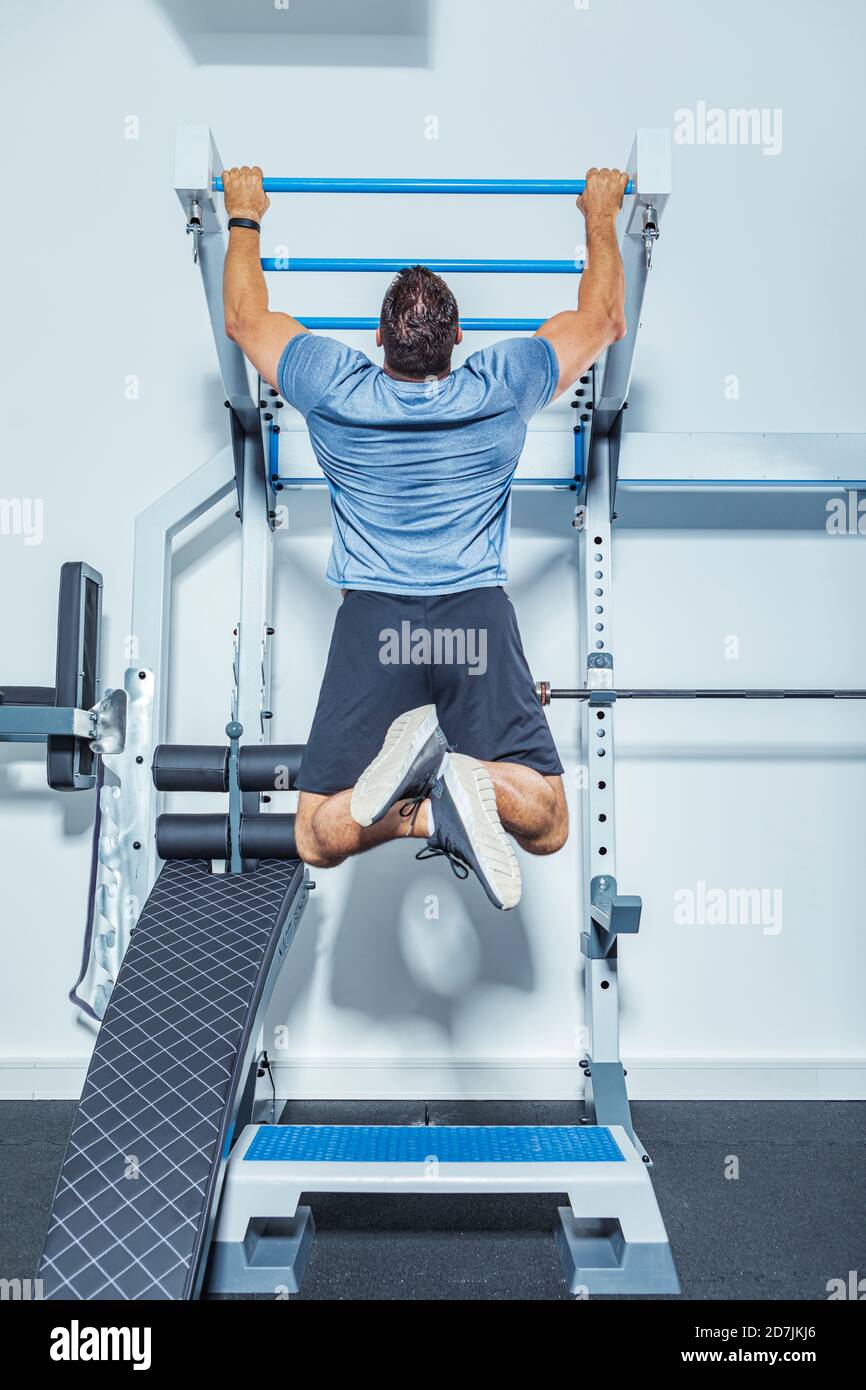 Male athlete exercising on chin-ups bars in gym Stock Photo
