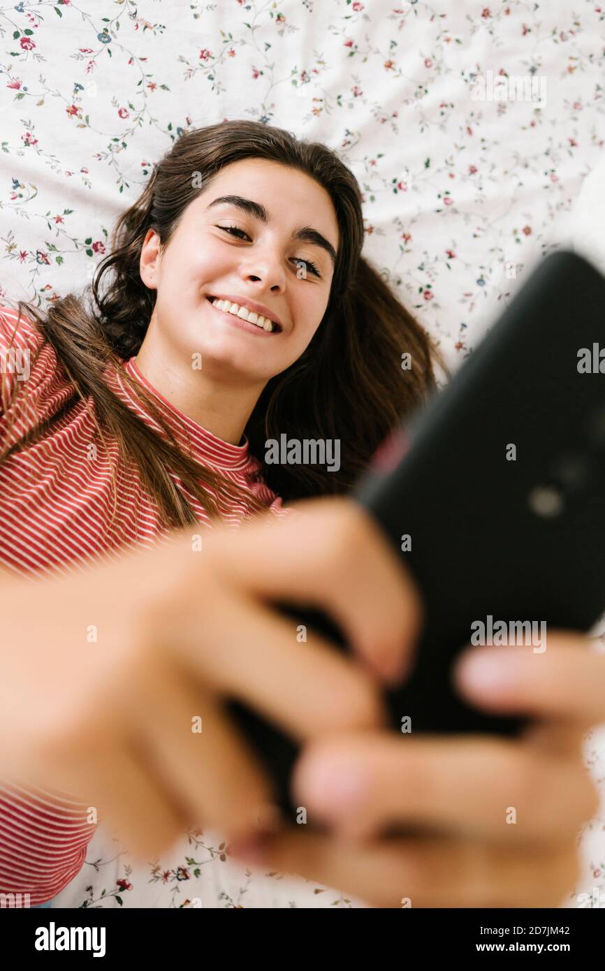 Woman taking selfie on smart phone in bedroom Stock Photo