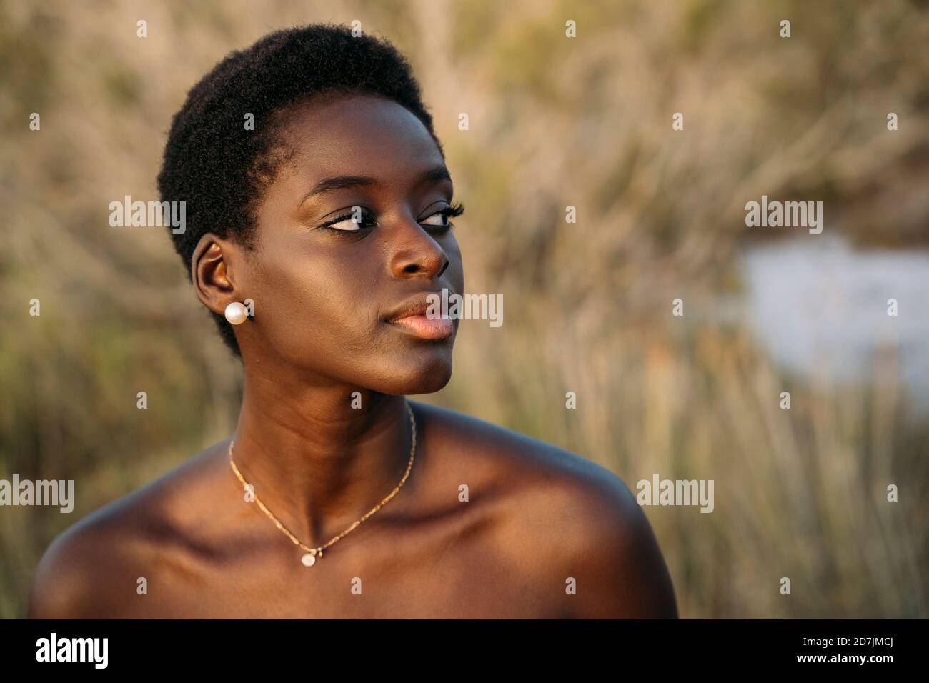 Beautiful woman looking away while standing at field Stock Photo