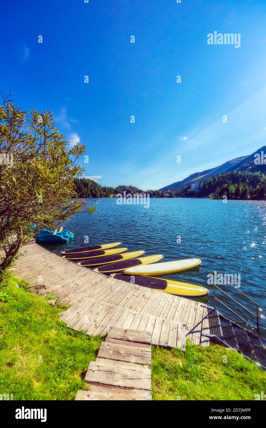 Boat and surfboard tied at jetty in lake against clear sky at Turracher Hoehe, Gurktal Alps, Austria Stock Photo