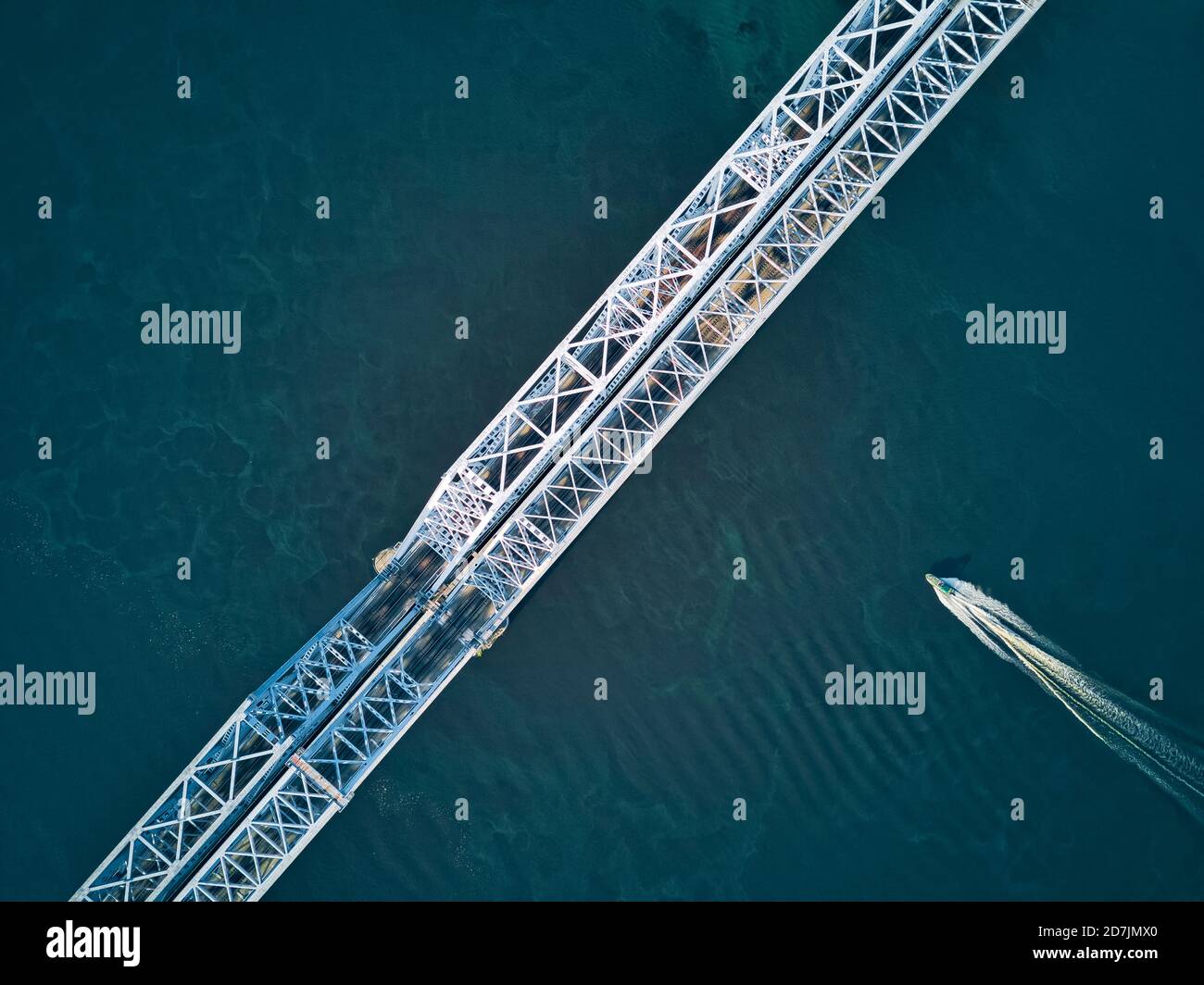 Directly above aerial view of boat moving over Volga River under metallic railway bridge Stock Photo