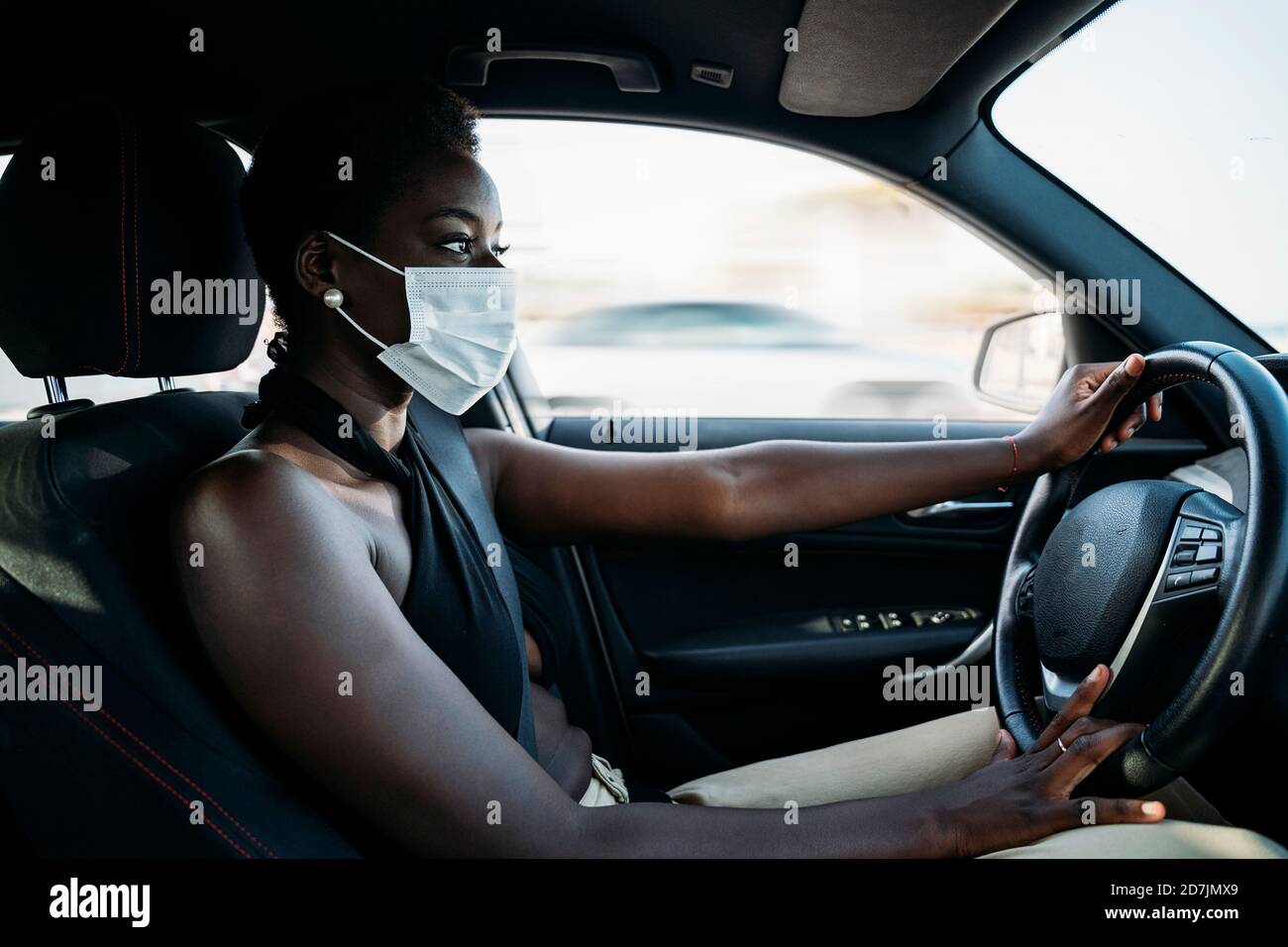 Young woman wearing face mask concentrating on driving car Stock Photo