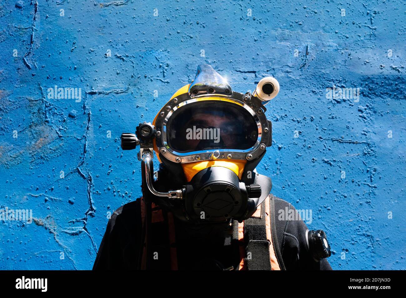 Close-up of male instructor wearing diving suit standing against blue wall Stock Photo