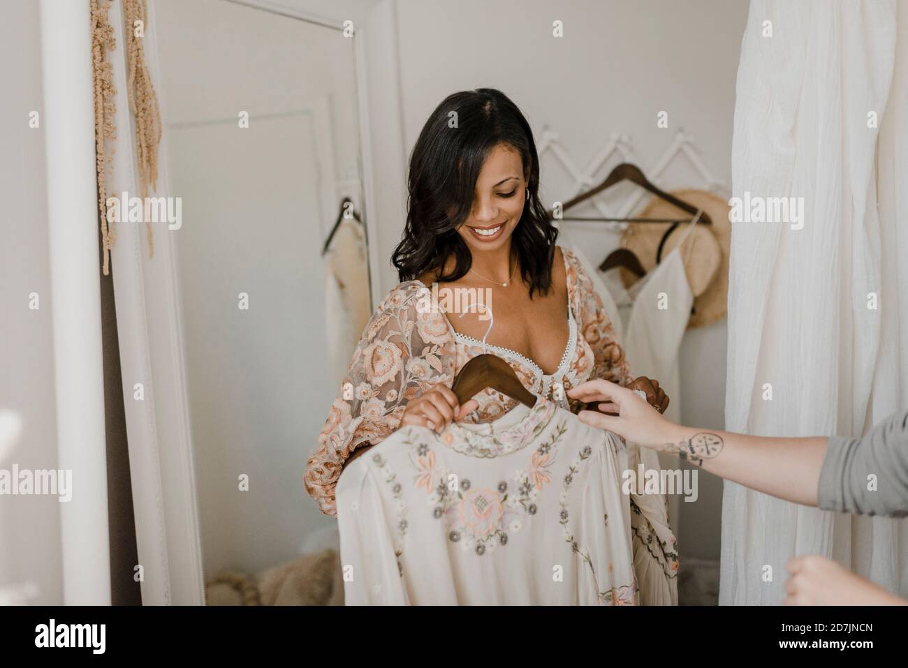 Cropped image of friend's hand trying new dress on bride at wedding dress shop Stock Photo