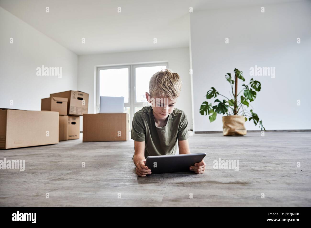 Boy lying down while playing on digital tablet in new house Stock Photo