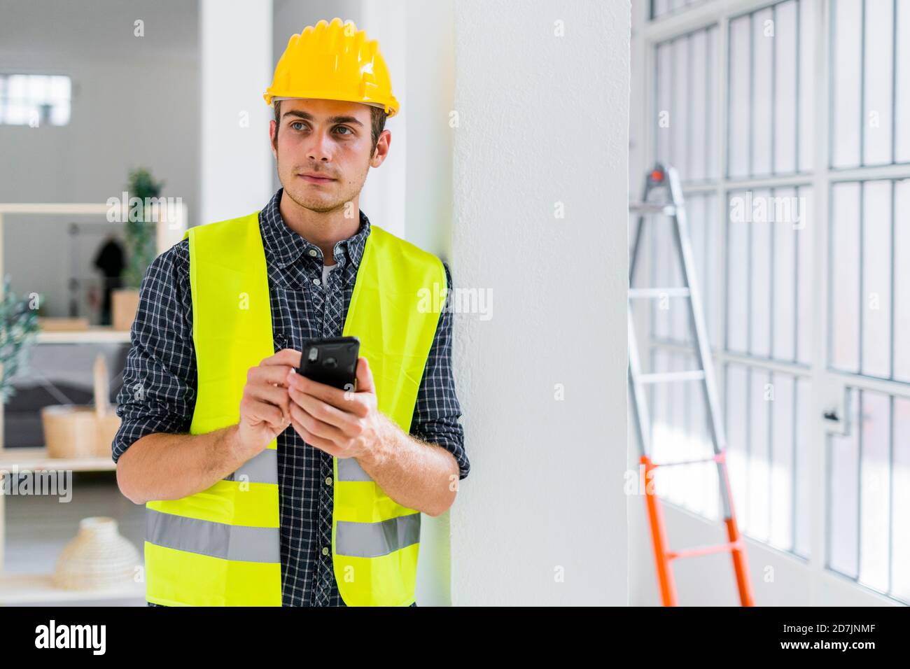 Architect using mobile phone while standing at office under construction Stock Photo