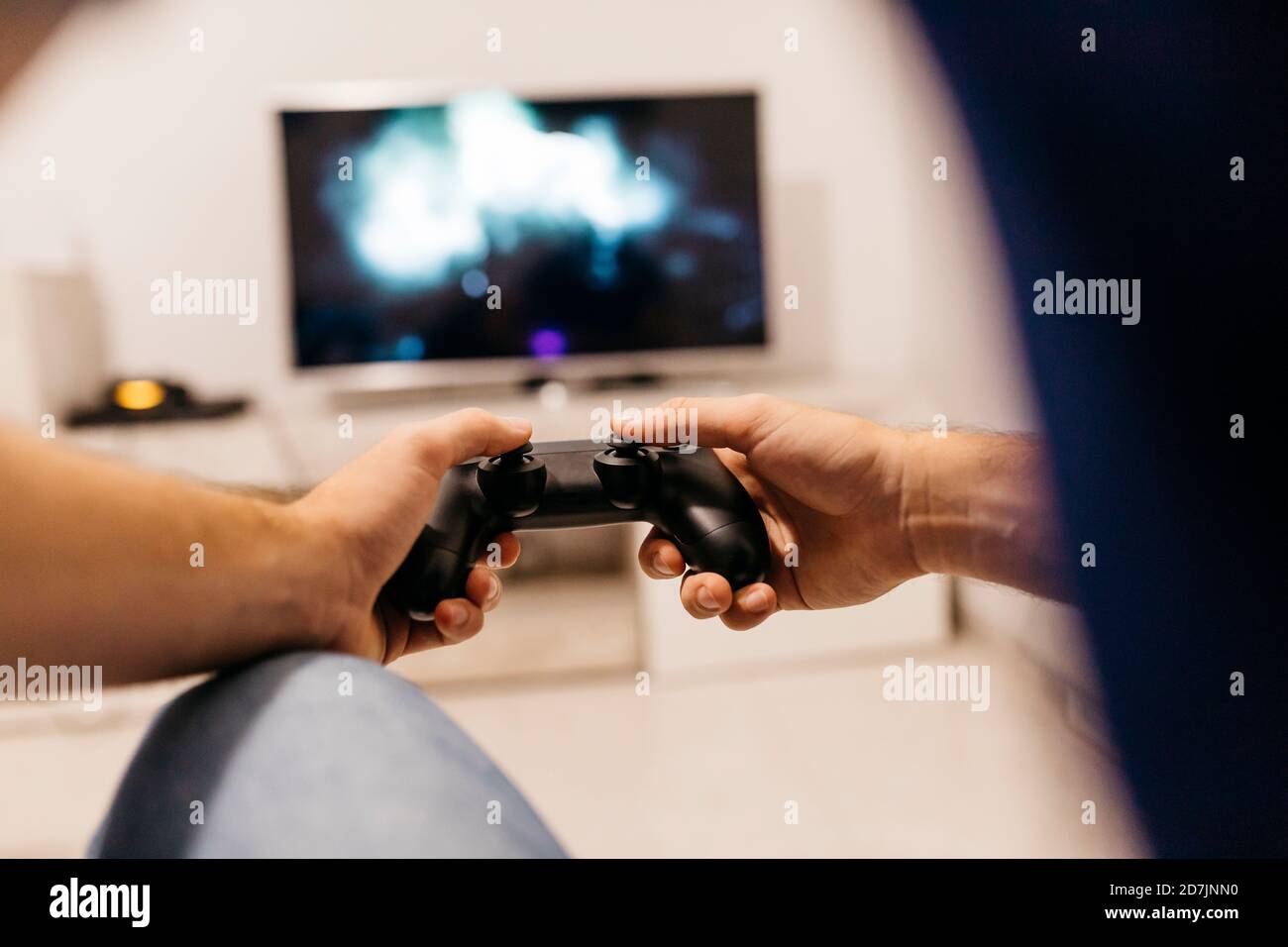 Hands of young male gamer holding controller while playing at home Stock Photo