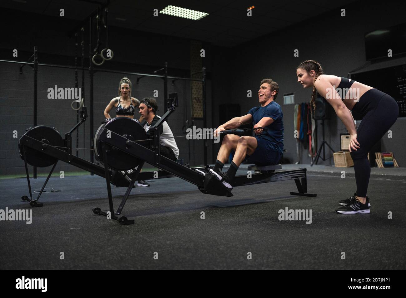 Athletes exercising with rowing machine at gym Stock Photo