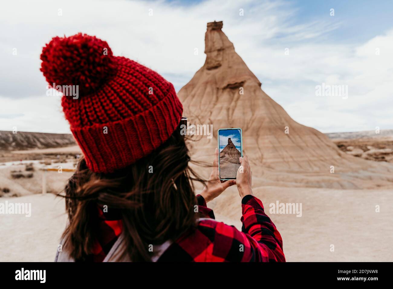 Spain, Navarre, Female tourist taking smart phone photos of sandstone rock formation in Bardenas Reales Stock Photo