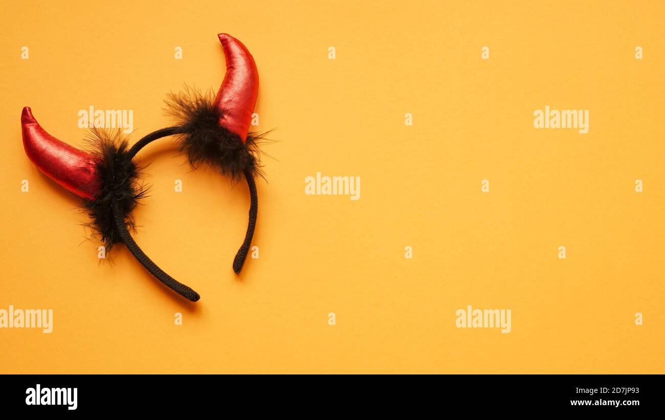 Red devil horns head hoop on orang background. Accessory for Halloween