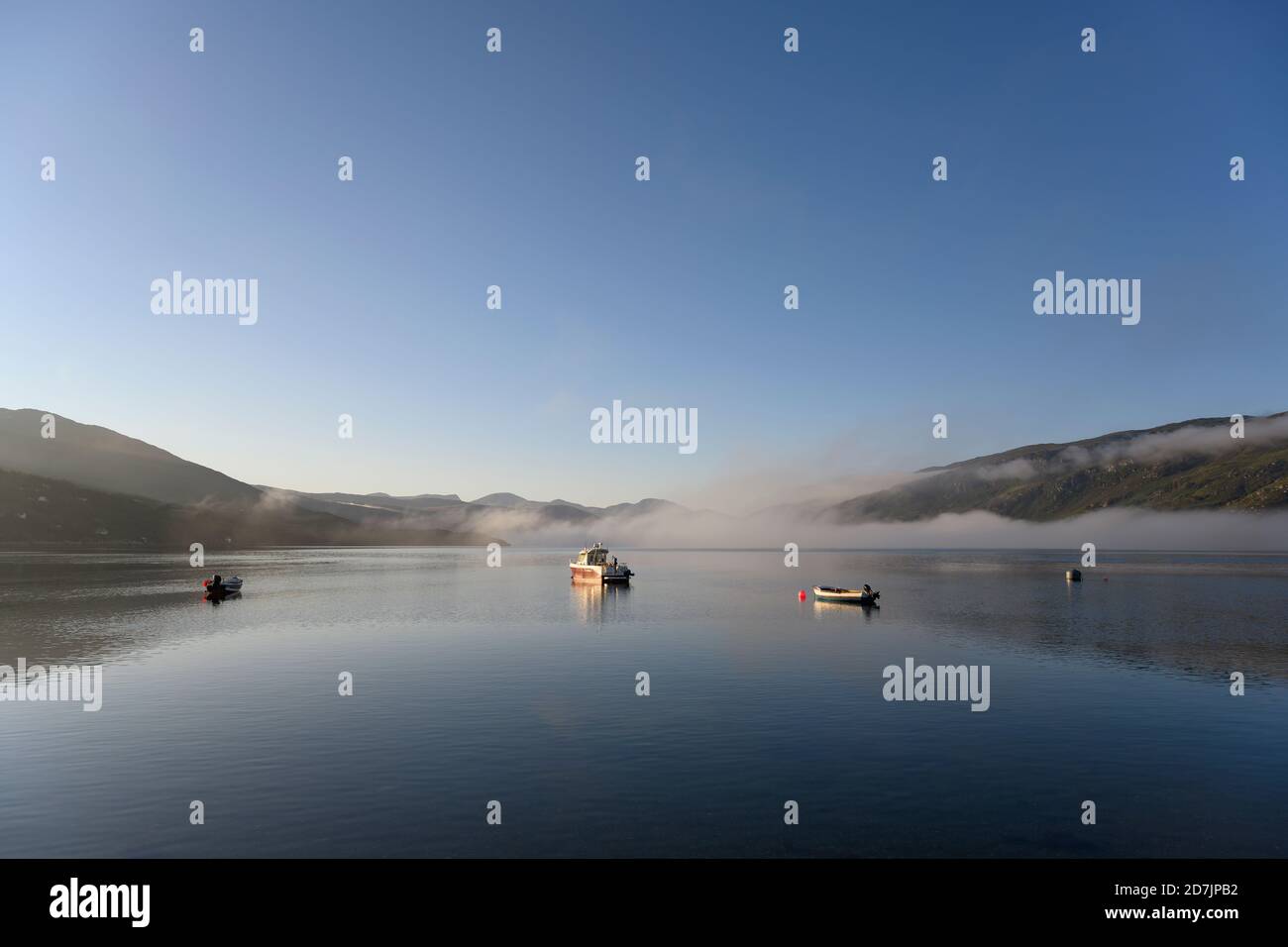 UK, Scotland, Ullapool, Clear sky over boats floating in Loch Broom during foggy weather Stock Photo