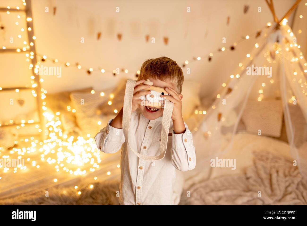 Cute blond boy playing with toy camera in room Stock Photo