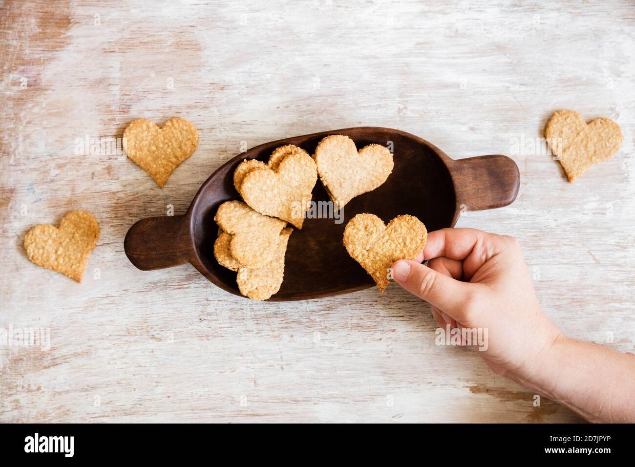 Hand of mature man picking up heart shaped oat cookie Stock Photo