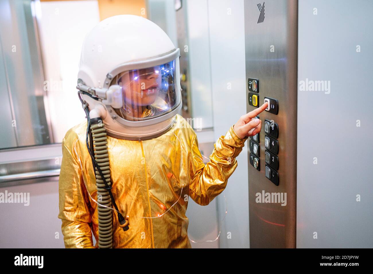 Boy wearing space suit pressing buttons in elevator Stock Photo