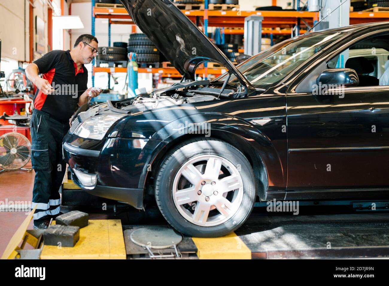 Male mechanic repairing car while standing in auto repair shop Stock Photo