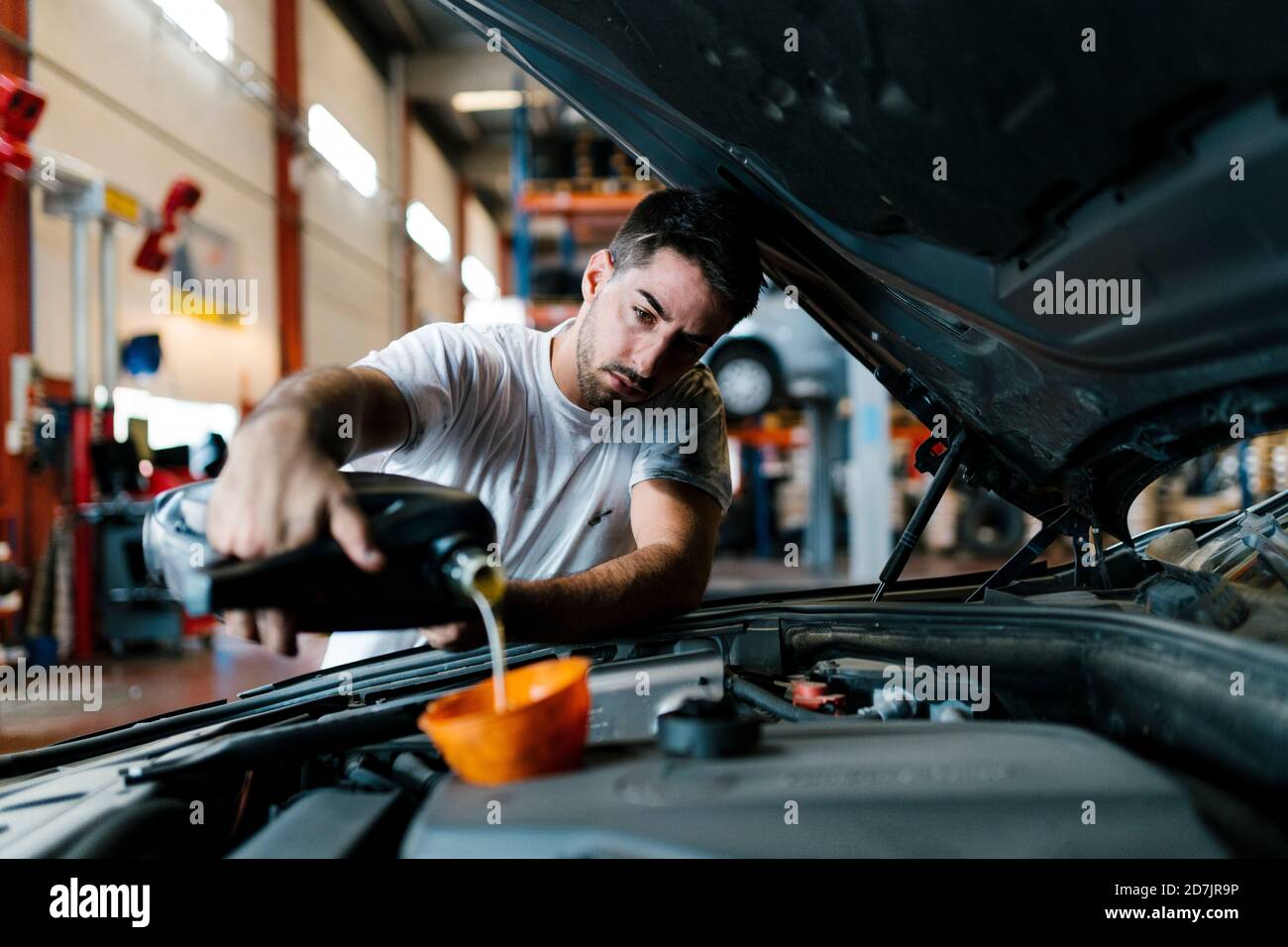 Auto mechanic filling engine oil while standing in garage Stock Photo