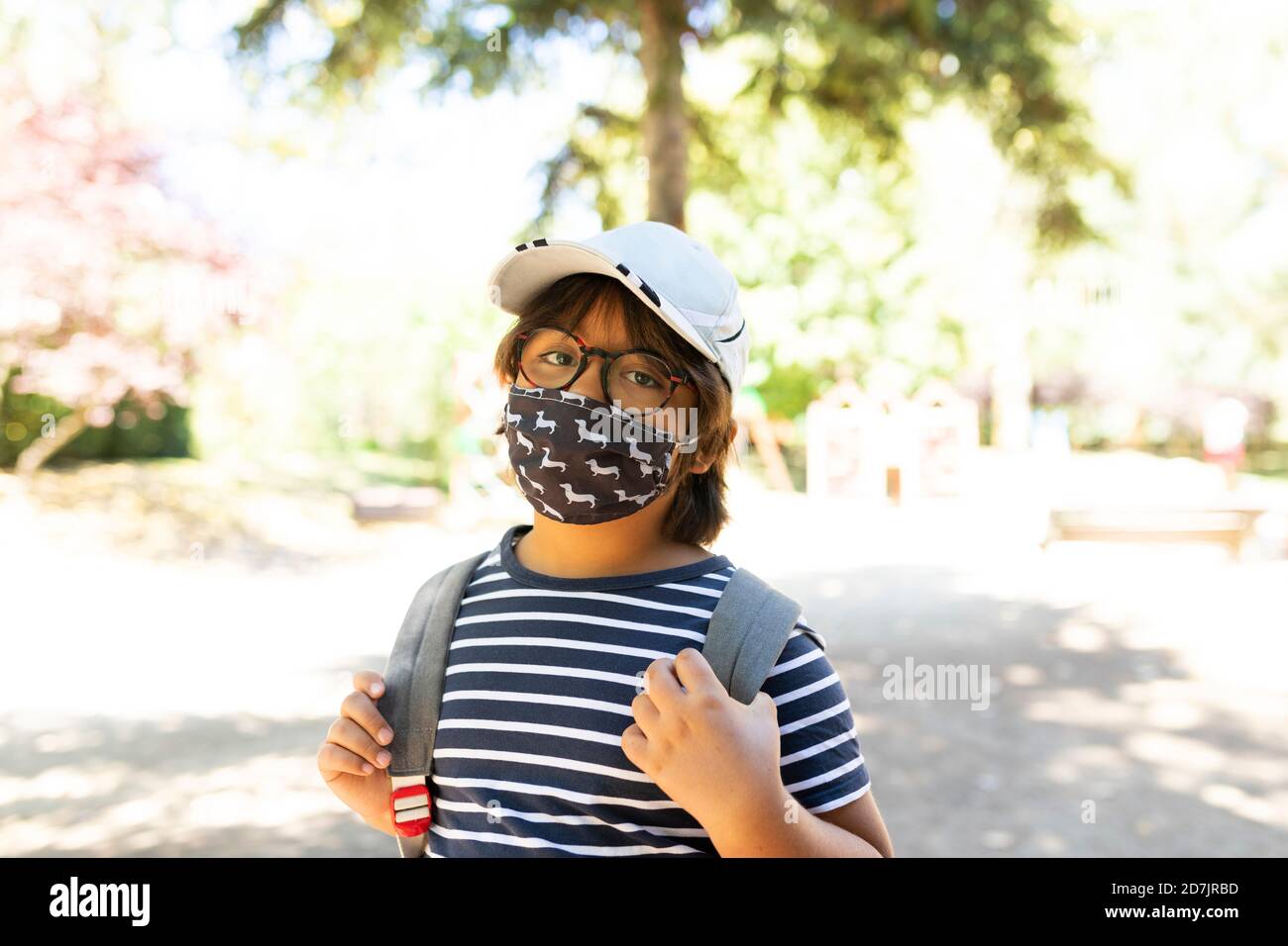 Schoolboy wearing mask standing on footpath Stock Photo