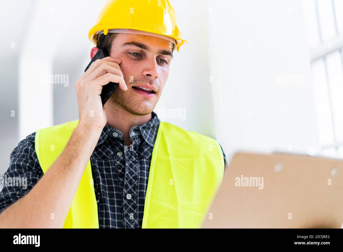Architect holding notepad while talking on mobile phone at construction site Stock Photo