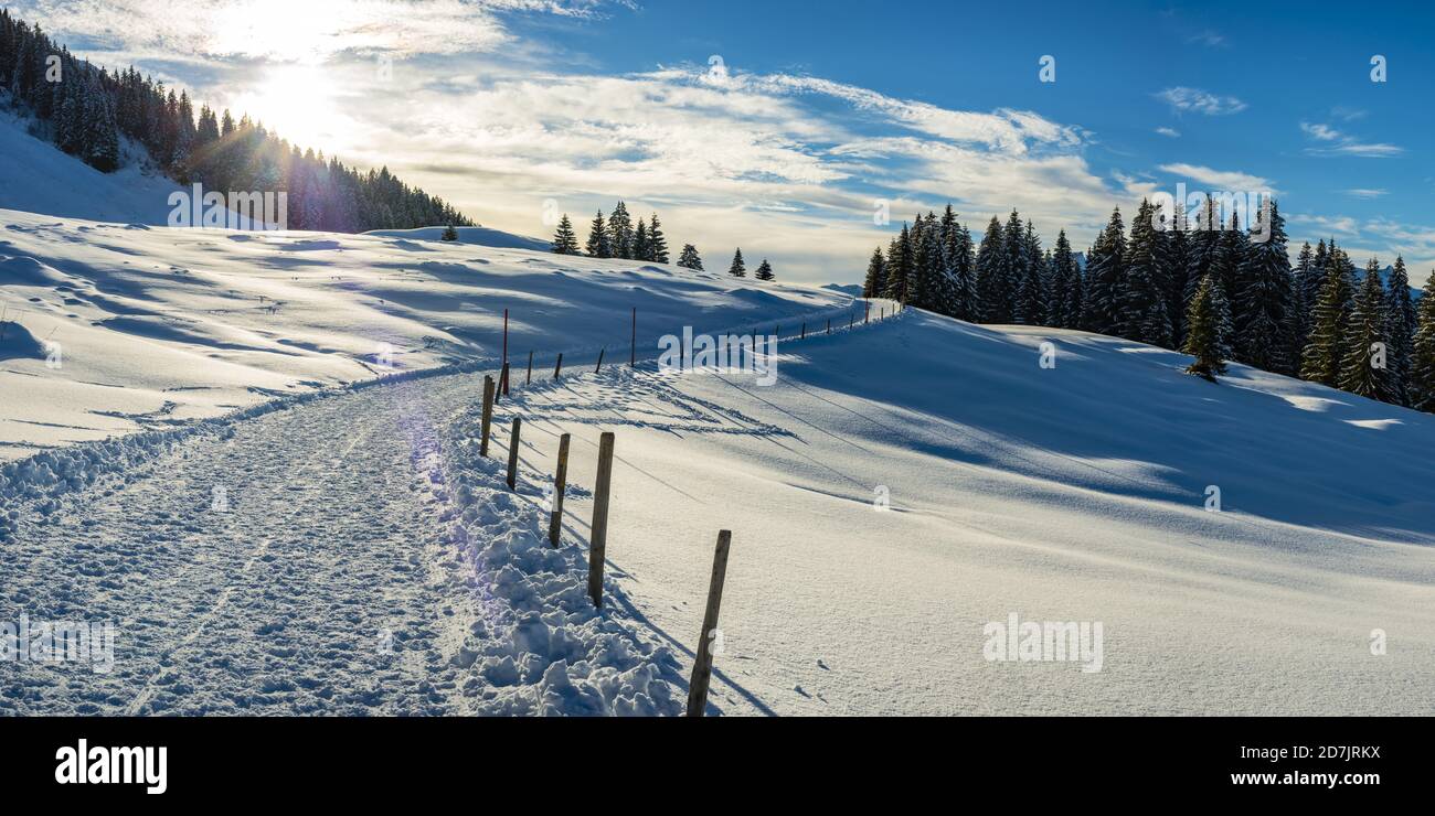 Sun setting over snow-covered footpath in Kleinwalsertal Stock Photo