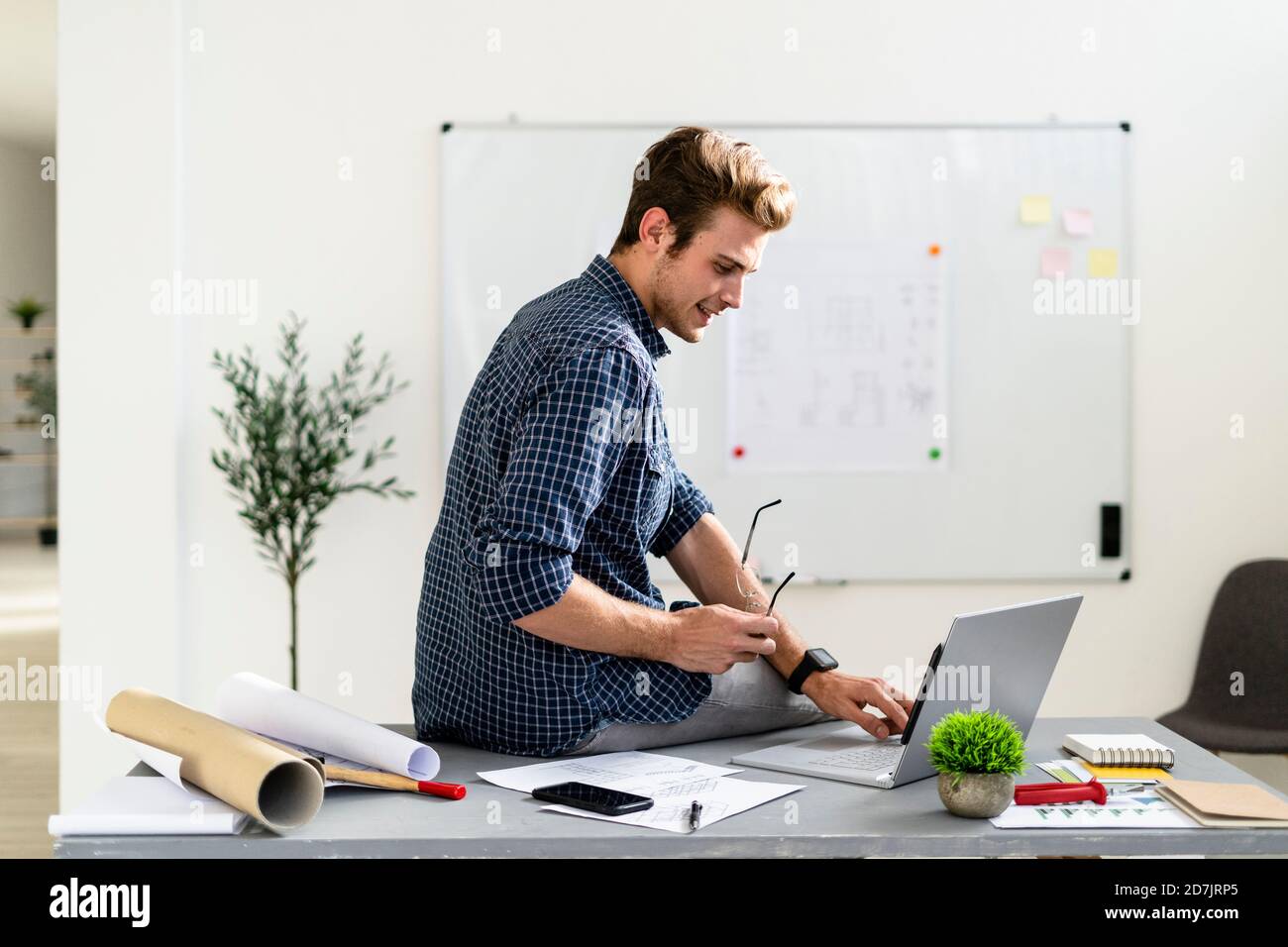 Young man using laptop while sitting on desk at office Stock Photo
