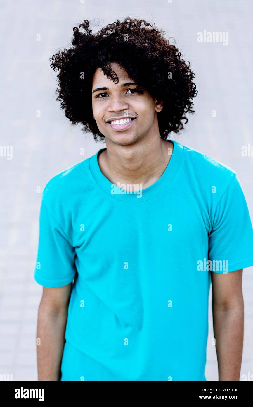 Smiling young man standing against wall Stock Photo