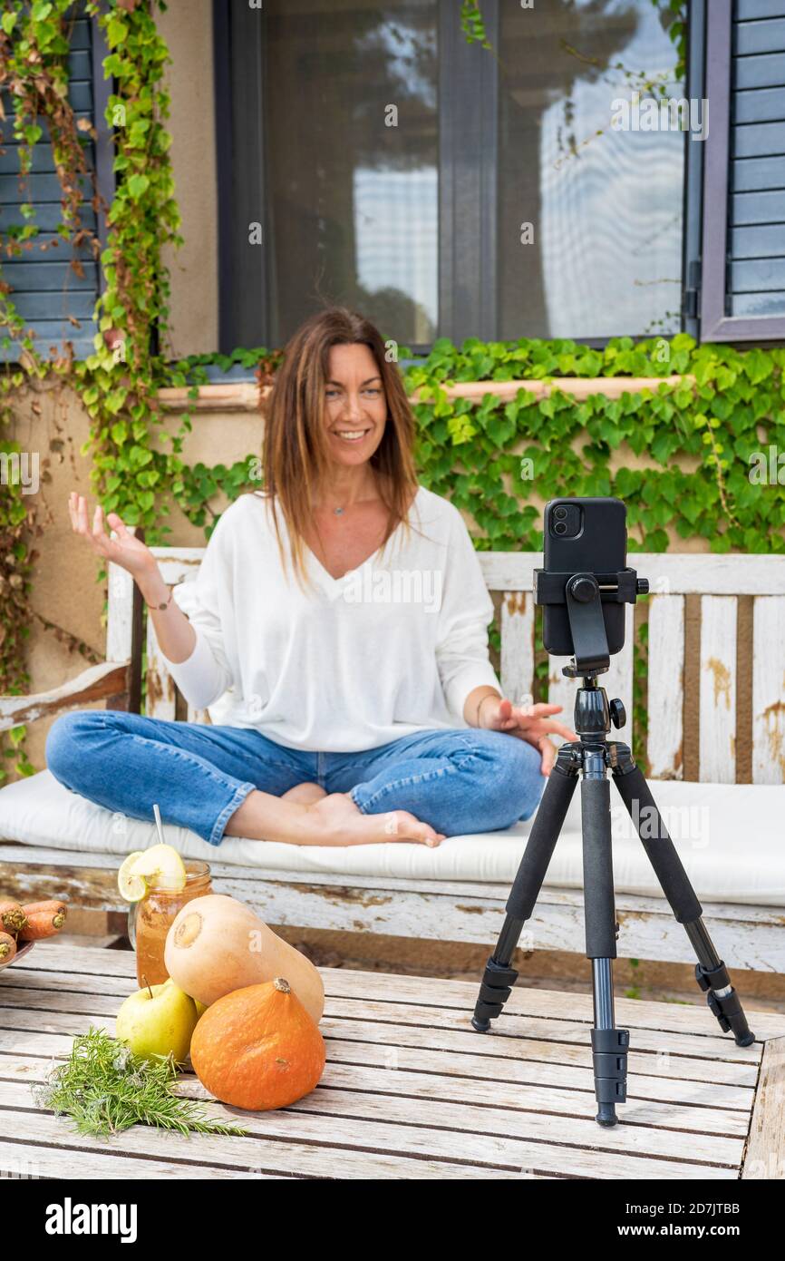 Smiling female nutritionist vlogging through smart phone at back yard Stock Photo
