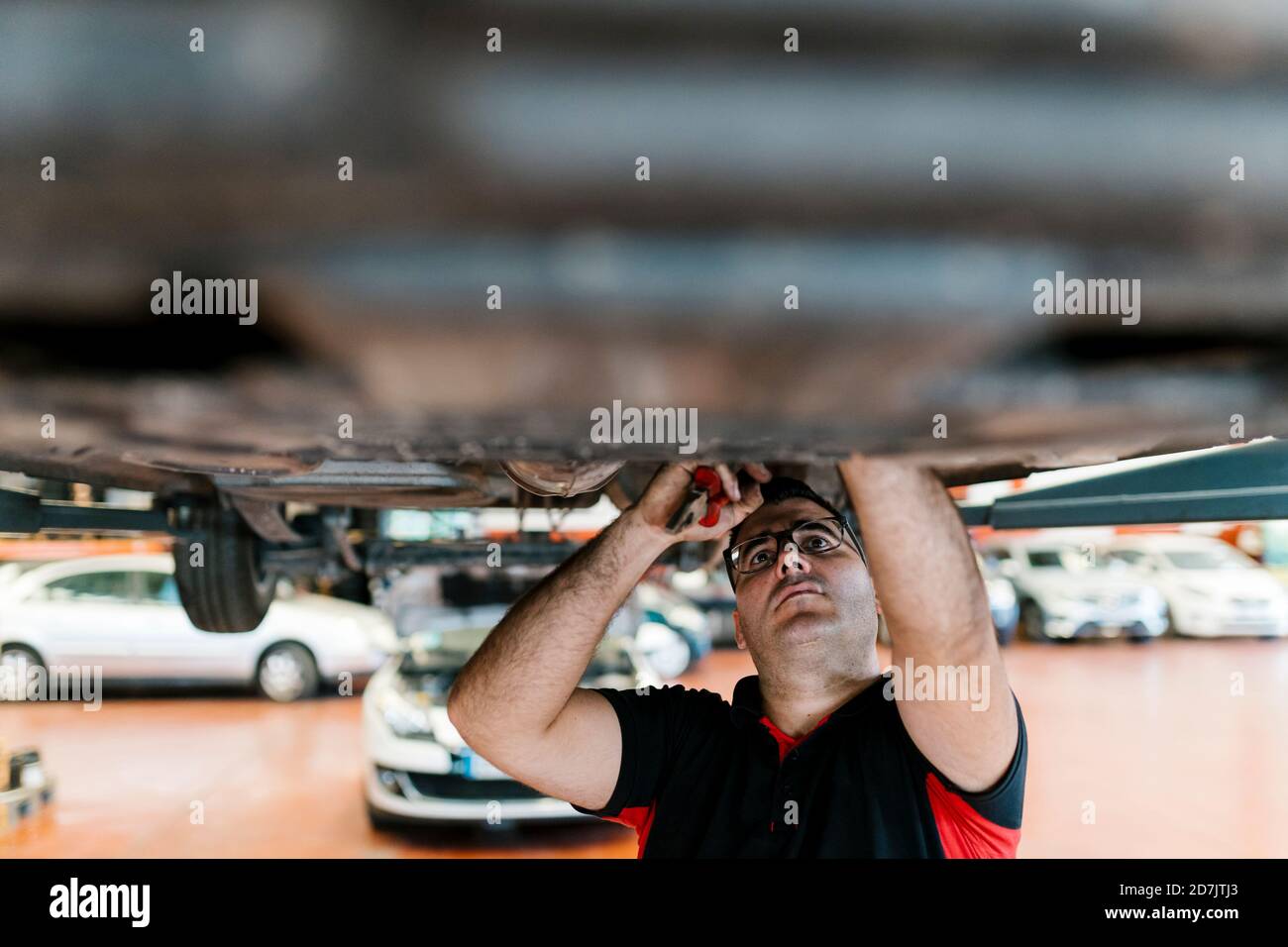 Mid adult man examining car in auto repair shop Stock Photo