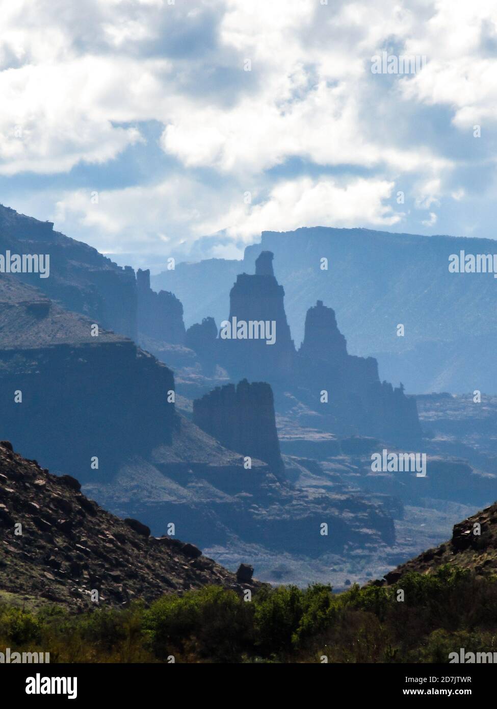 The Fisher Towers, in the distance with only the blue silhouettes really visible, as seen just as you enter Castle Valley, in Moab, USA Stock Photo