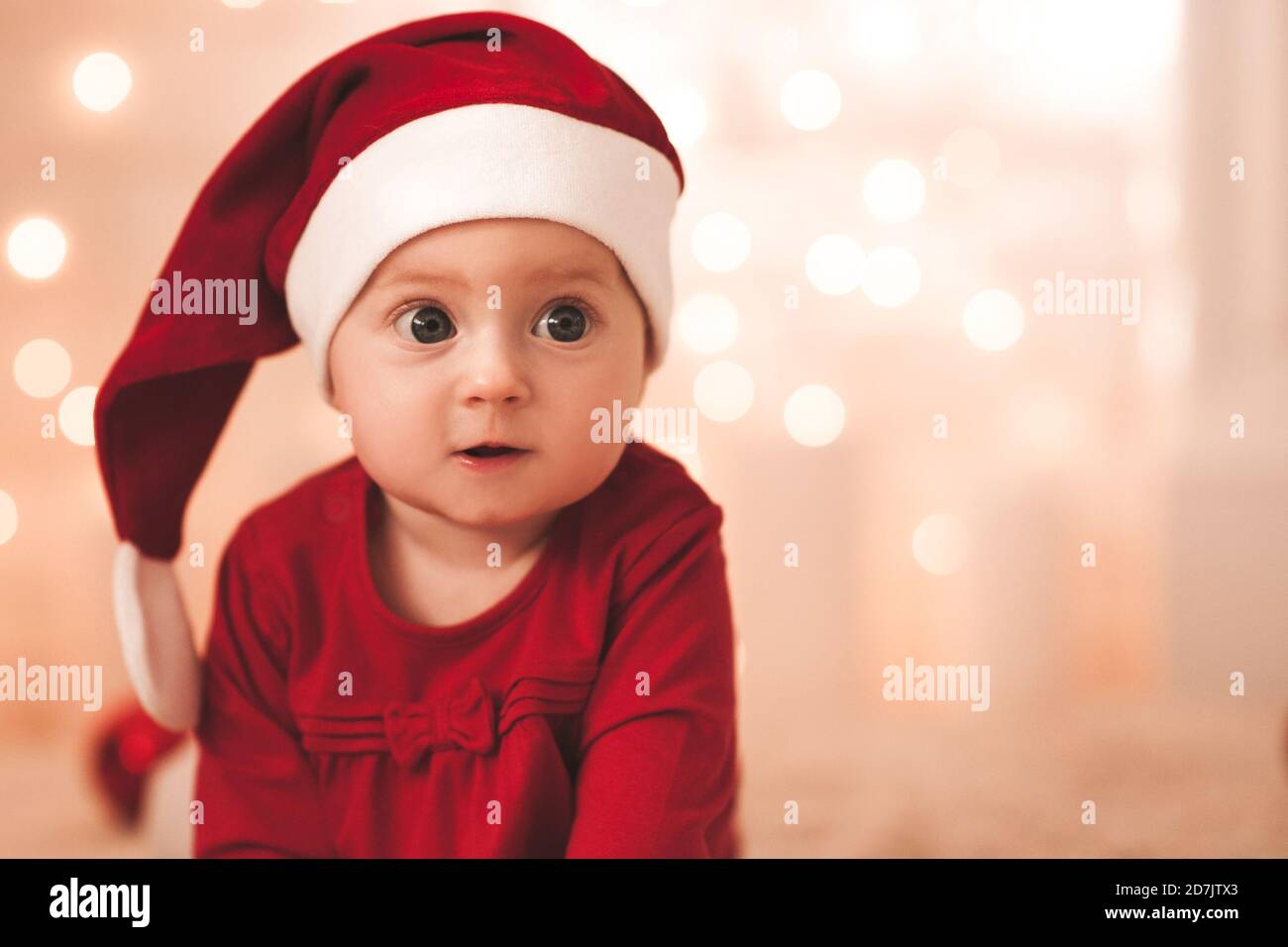 Cute baby girl 1 year old wearing red santa hat and dress over glowing  Christmas lights in room closeup. Winter holiday season. Childhood Stock  Photo - Alamy