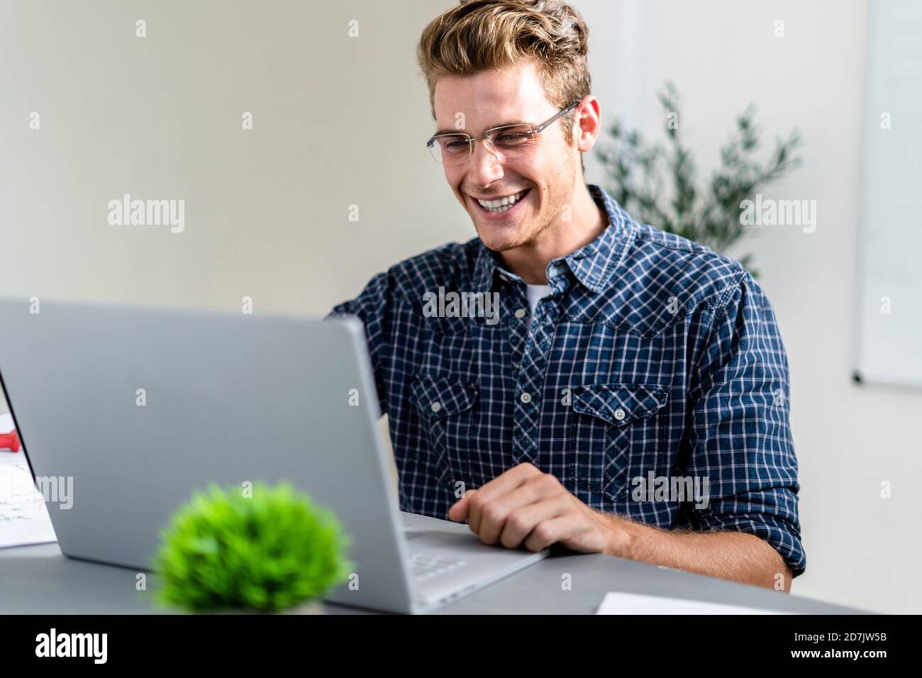 Smiling man using laptop while sitting at office Stock Photo