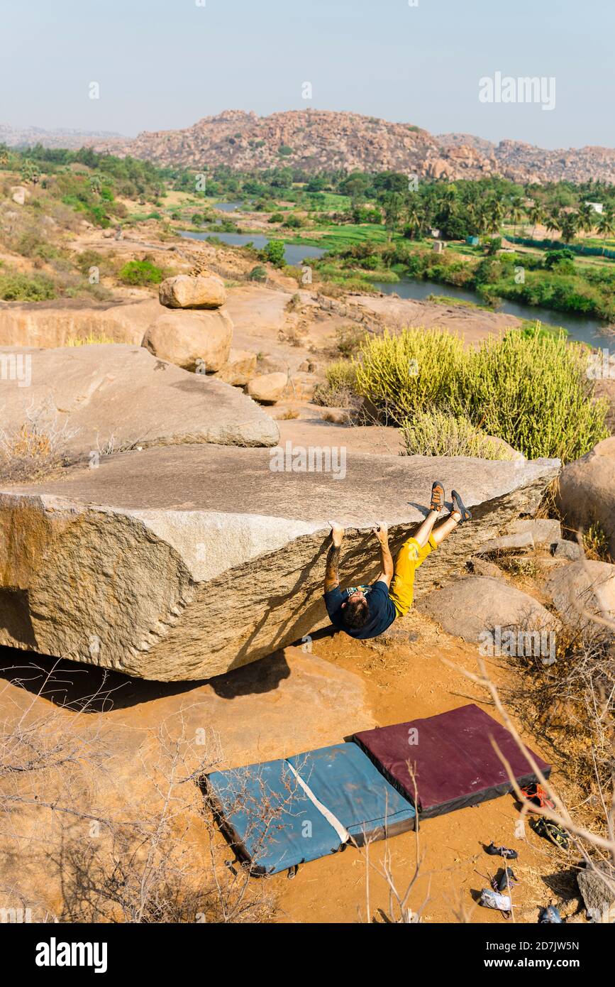 Male rock climber getting on top of boulder Stock Photo