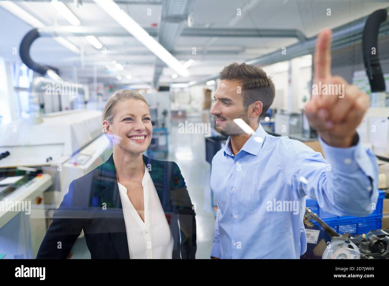 Young male technician pointing at graphical interface on glass in factory Stock Photo