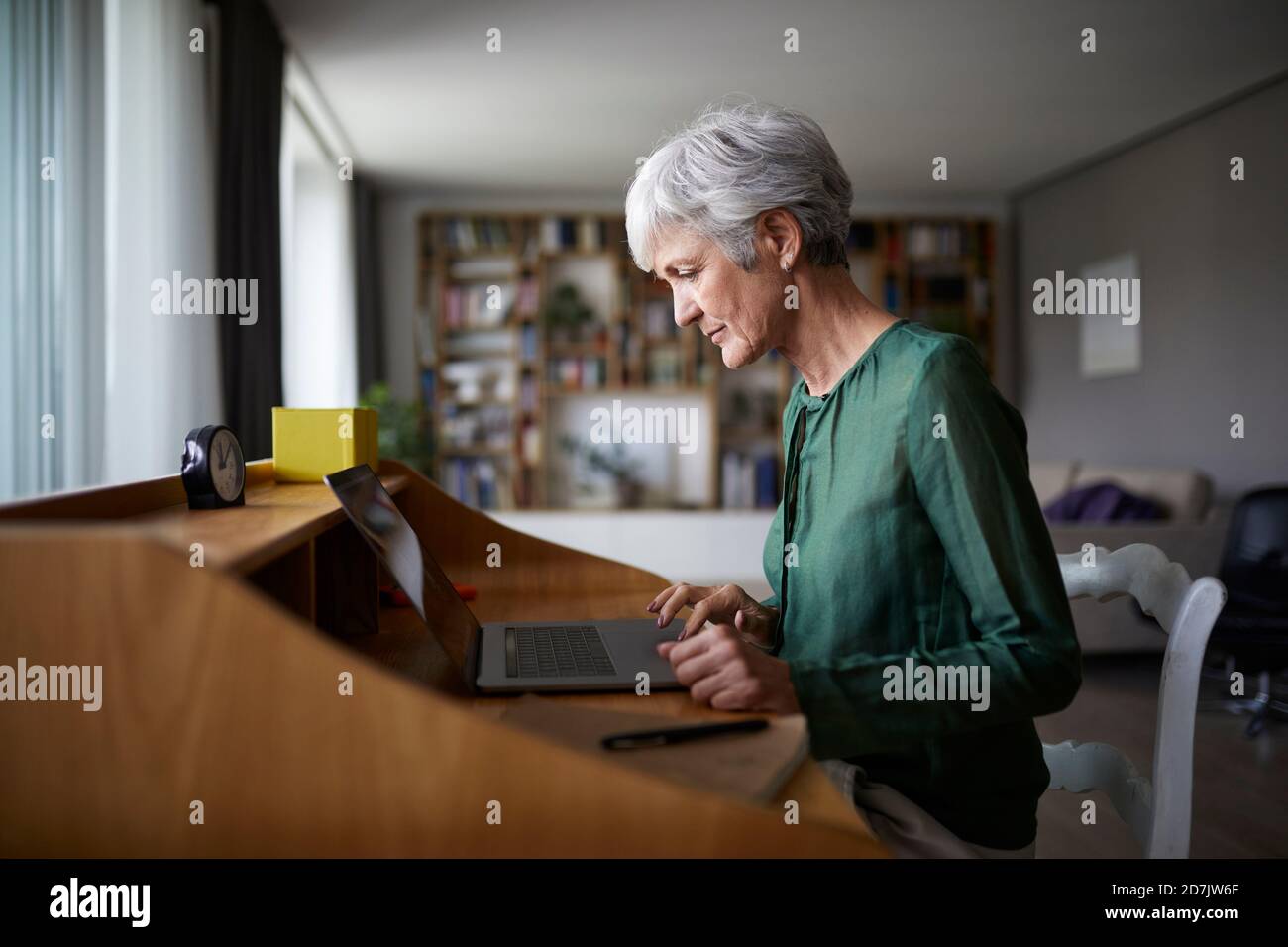 Active senior woman concentrating while working on laptop Stock Photo