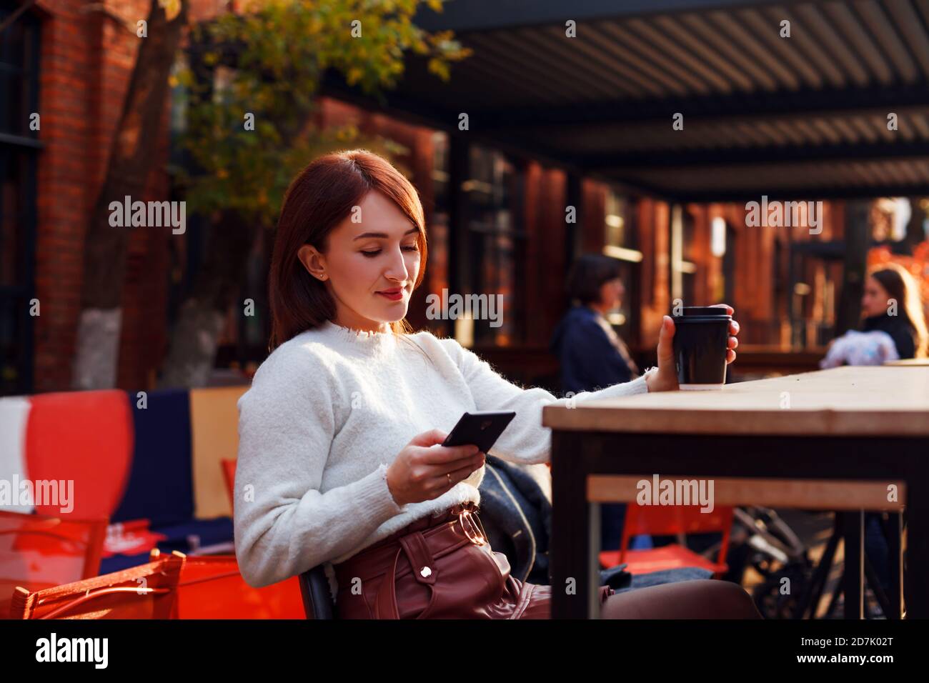 Online dating concept. Smiling young woman reading message from her smartphone. Stock Photo