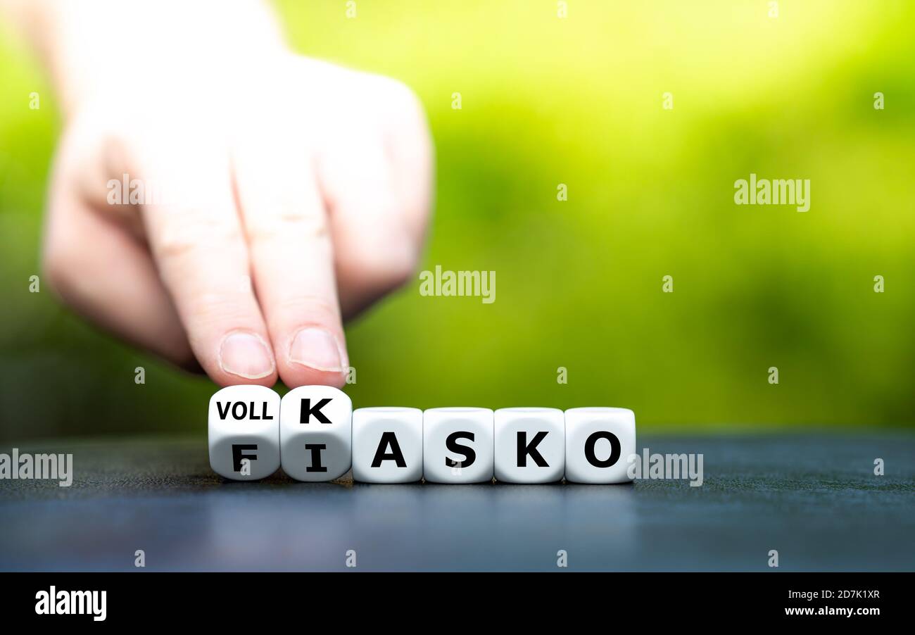 Hand turns dice and changes the German expression 'Fiasko' (fiasco) to 'Vollkasko' (comprehensive coverage). Stock Photo