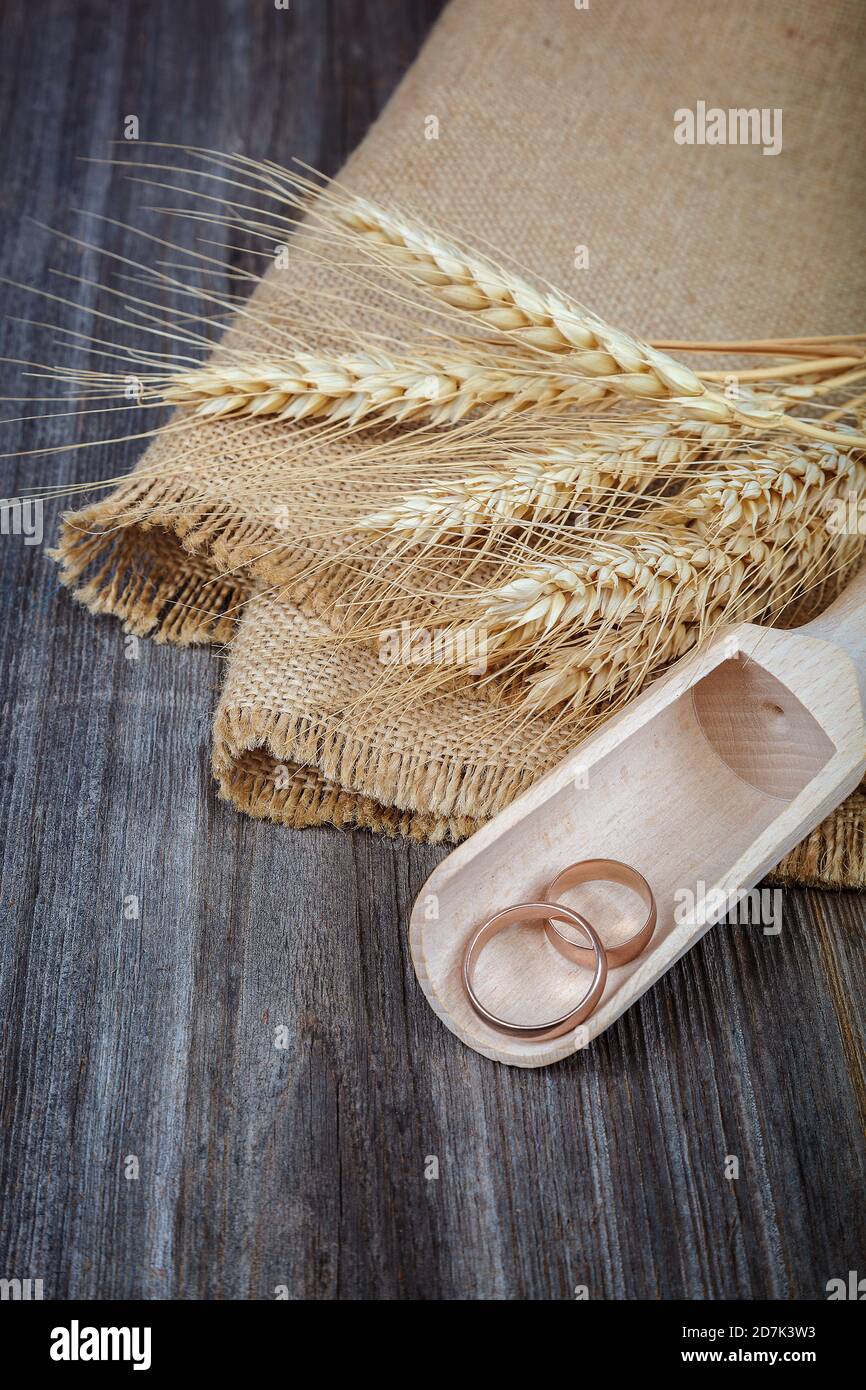 Wedding rings in a wooden scoop and ears of wheat on the wooden ...