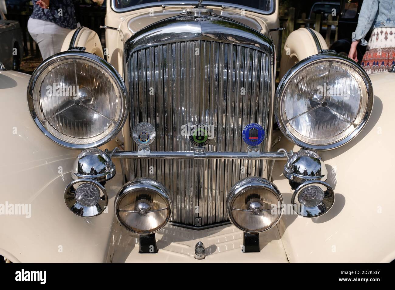 close up of 1930s Bentley car chrome radiator grill with headlamps, horns and badge bar against cars cream bodywork. Concourse condition. Stock Photo