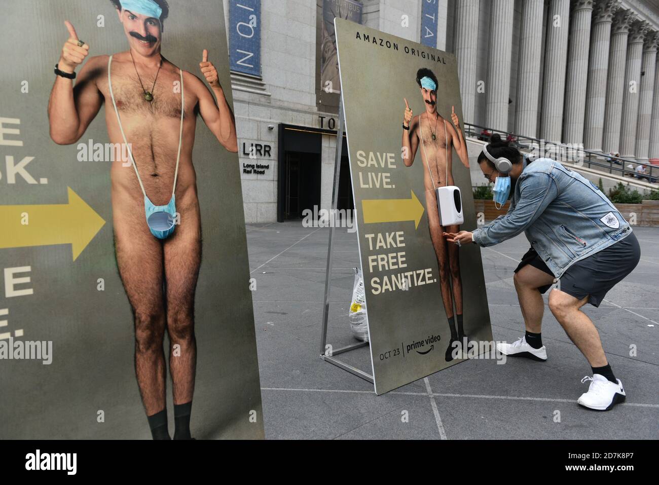 New Yorkers take a free face mask from a lifesize poster of Sacha Baron Cohen as part of a promotion for the new film titled ‘Borat Subsequent Moviefi Stock Photo