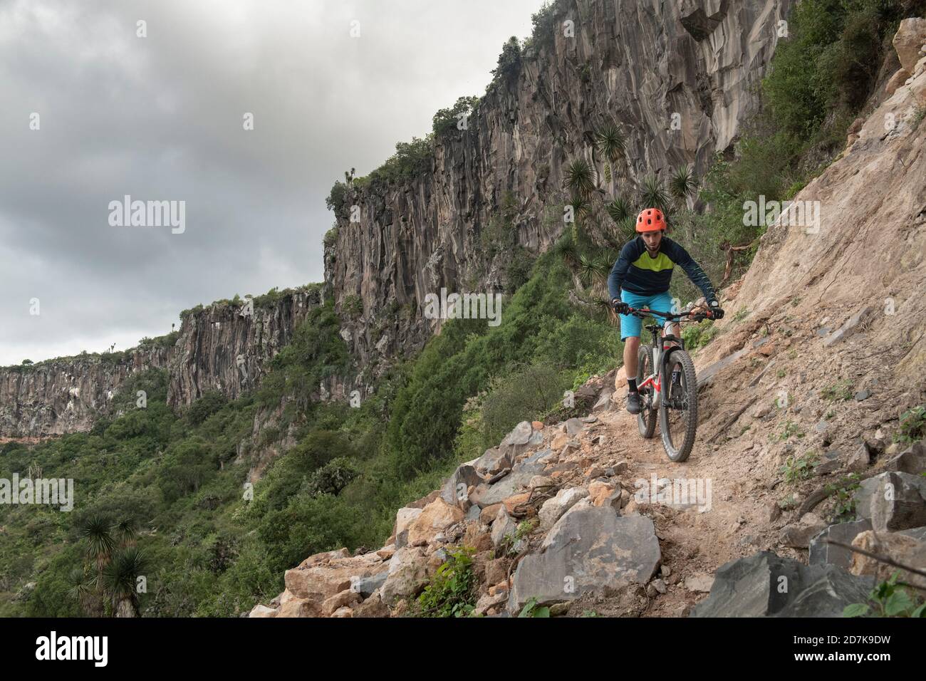 A man riding down a mountain bike on a narrow rocky trail at a canyon ...