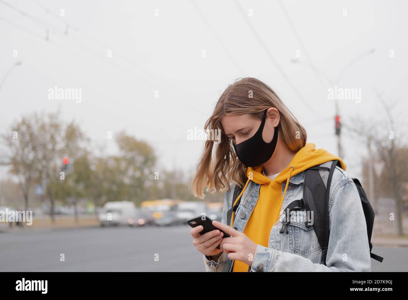 Portrait of a woman in mask with smartphone. Being outdoors in covid world, urban scene Stock Photo