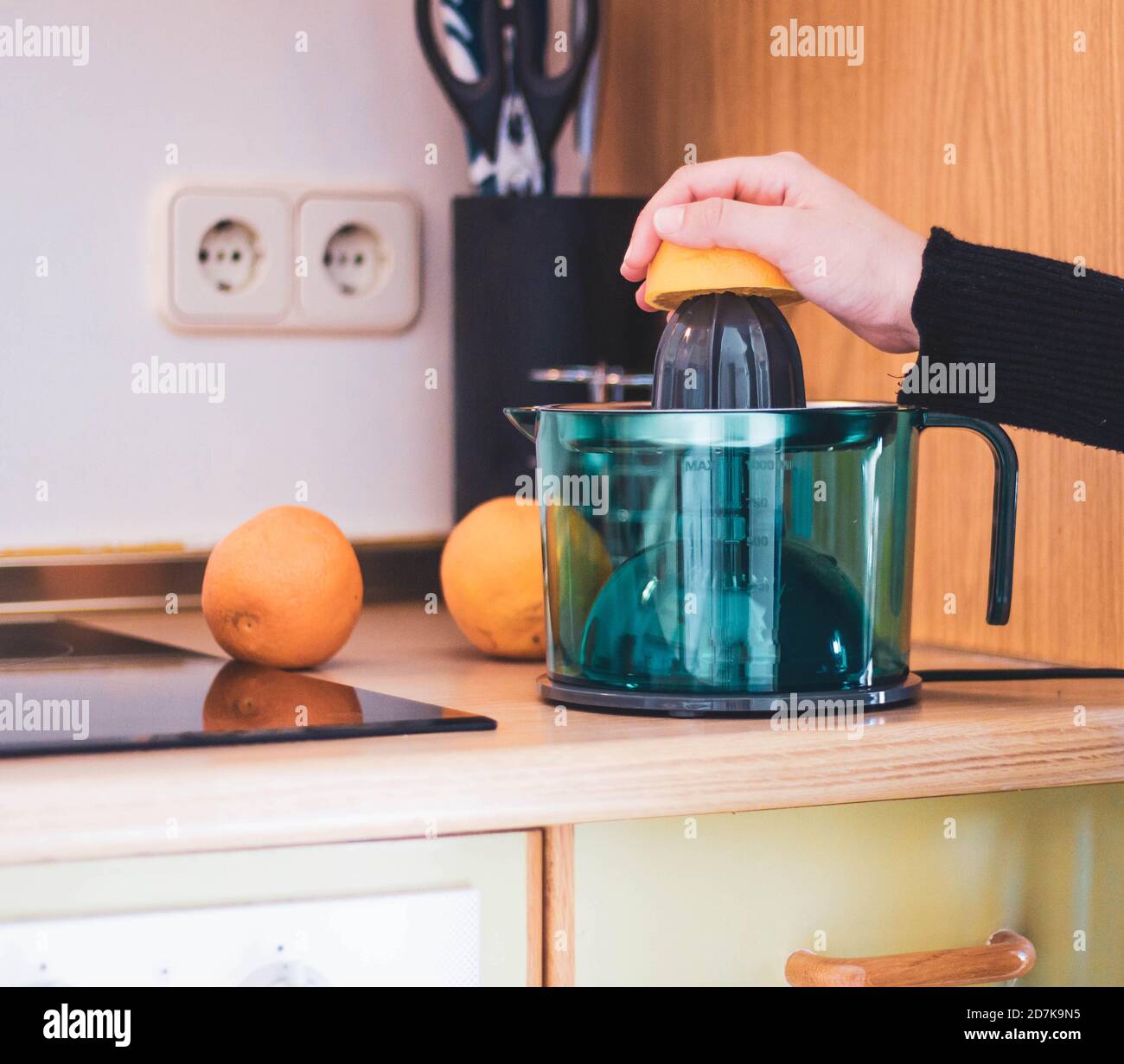 woman's hand squeezing oranges in the kitchen Stock Photo